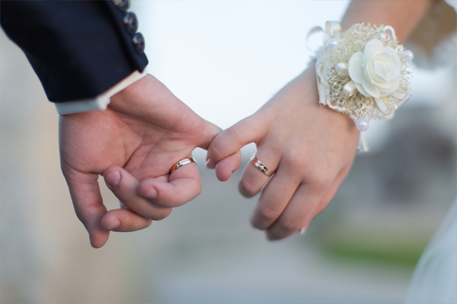 Image of a couple holding hands during their wedding.