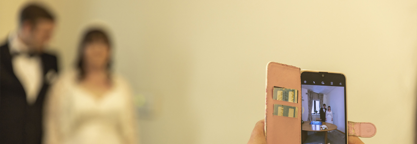 Image of someone taking a photo of the bride and groom.